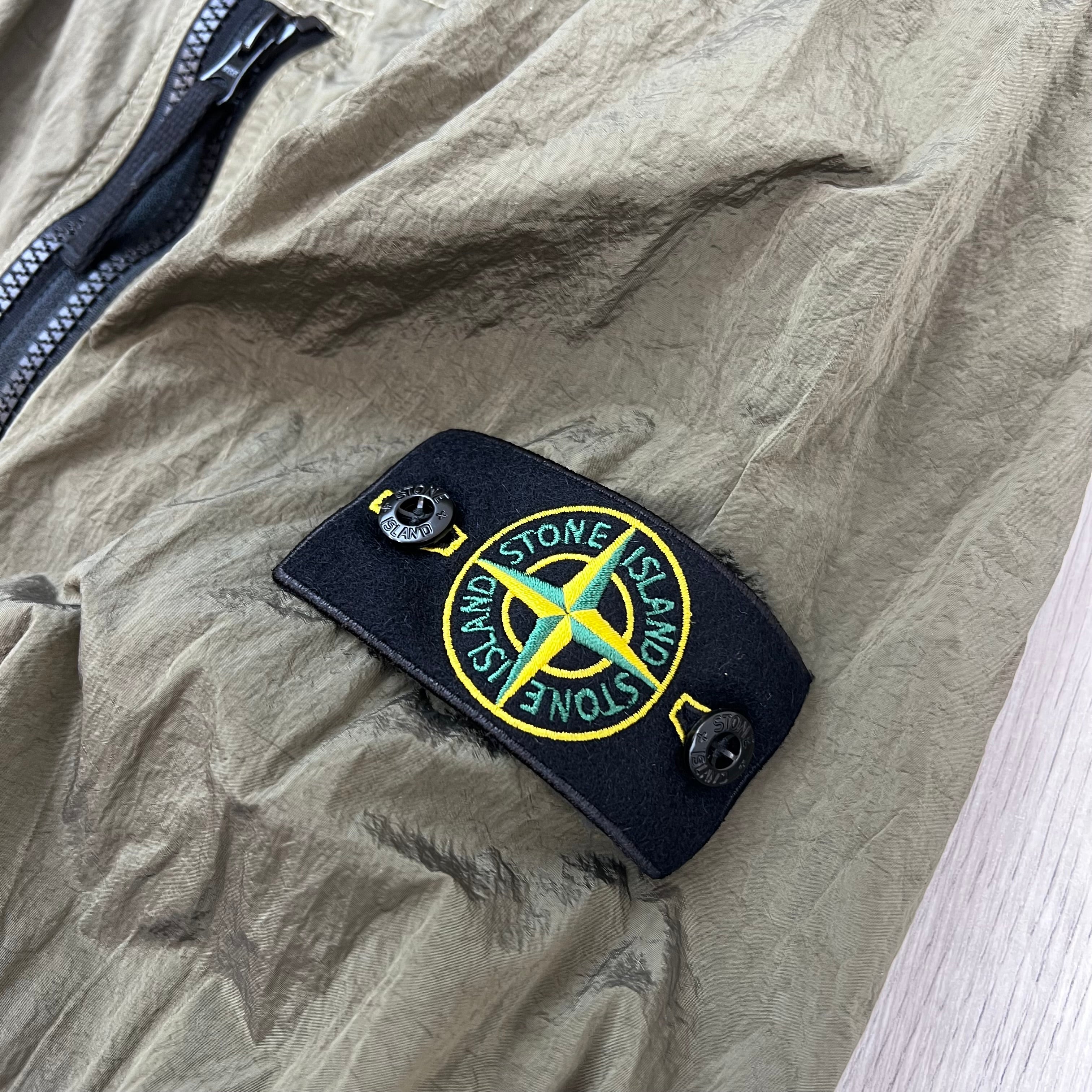 A close view of the compass badge on a Stone Island Nylon Metal Overshirt in Military Green.